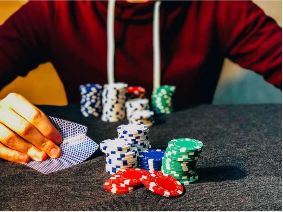 Image of a poker player sitting at a table with stack of poker chips